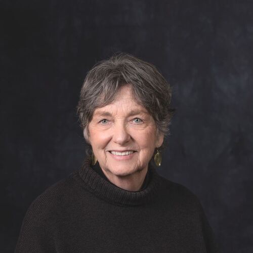 Deborah Penrose smiling in a professional headshot, wearing a dark turtleneck sweater