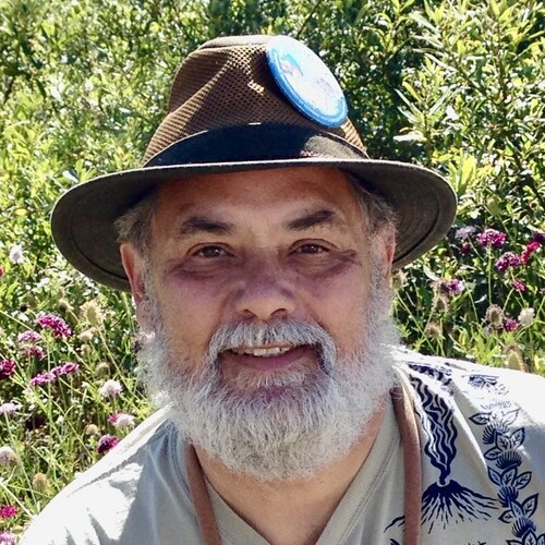 Rick Bonilla smiling outdoors, wearing a wide-brimmed hat with a gray beard