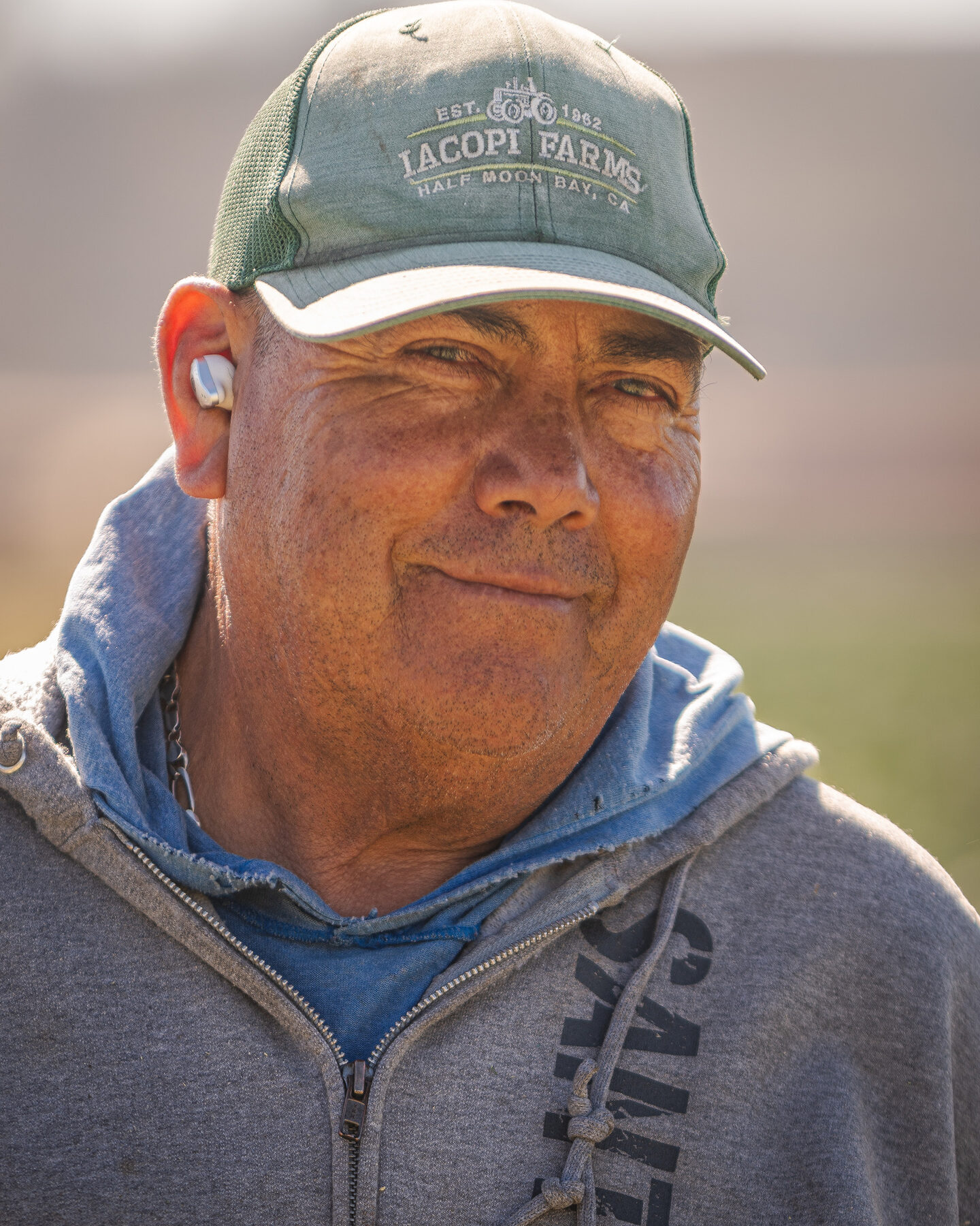 Senior farmworker wearing an Iacopi Farms cap, smiling